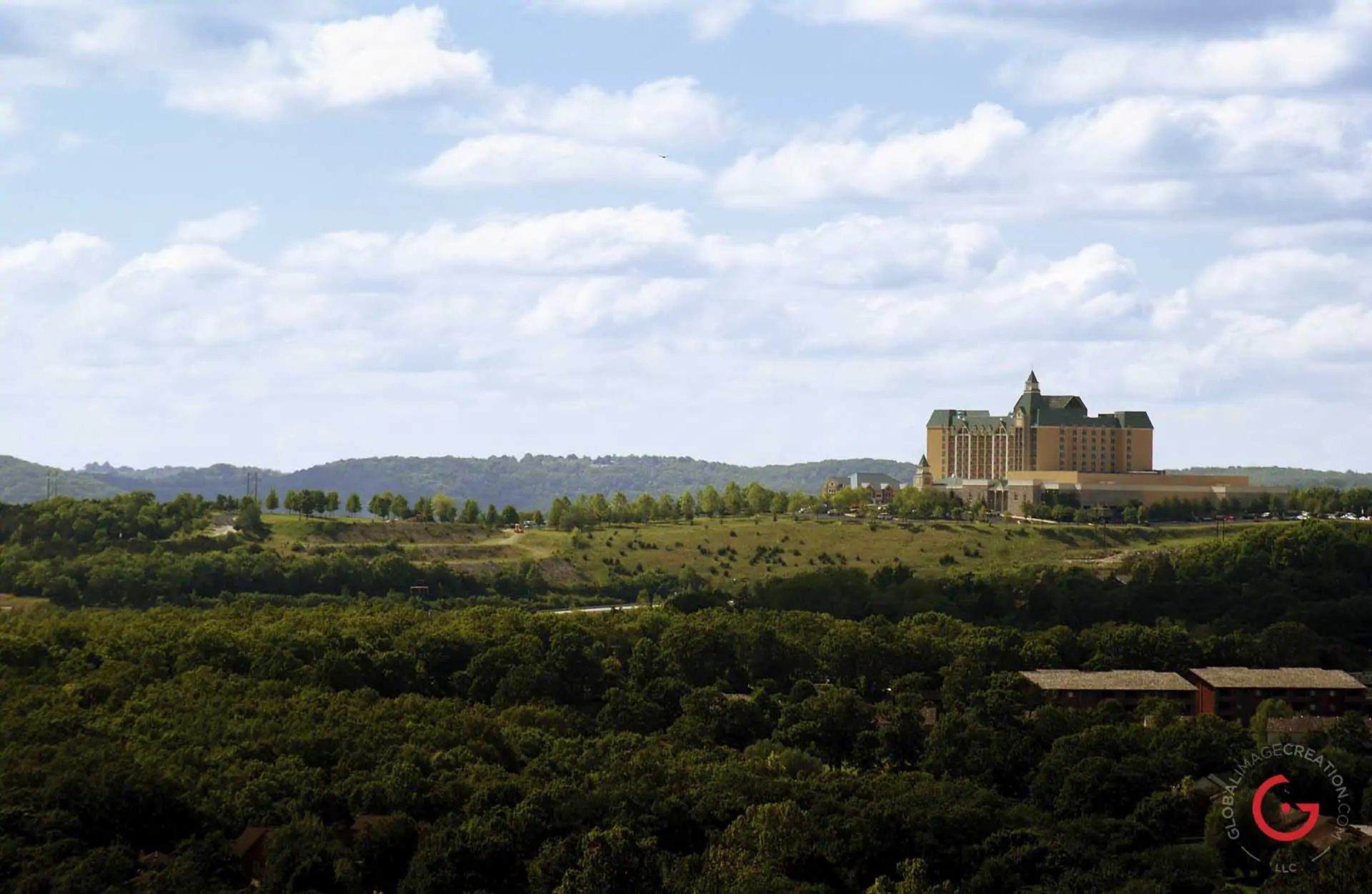 The Chateau on the lake hotel hovers on the horizon under light blue skies with puffy white clouds. - Advertising photographers in Branson Missouri, Branson Missouri photography