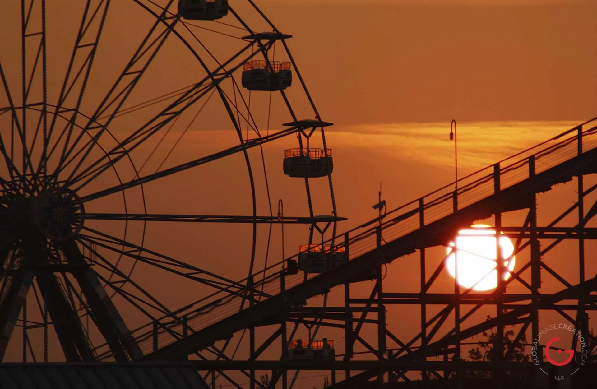An orange sunset silhouettes the Ferris wheel and roller coaster at celebration city. - Advertising photographers in branson Missouri, Branson Missouri photography