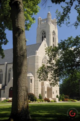 The Church at collage of the Ozarks under a bright blue sky with green grass and trees on the foreground.