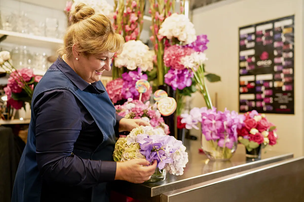 Florist Loren Fisher puts the finishing touches on a hotel room floral arrangement..